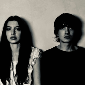 Members of the band Witch Post leaning against a wall in black and white.